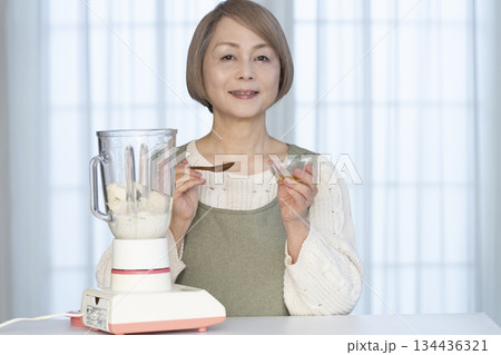 キッチンでヘルシージュースをジューサーで作るシニア女性 134436321