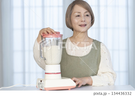 キッチンでヘルシージュースをジューサーで作るシニア女性 キッチンでヘルシージュースをジューサーで作るシニア女性 134436332
