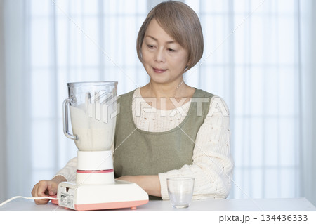 キッチンでヘルシージュースをジューサーで作るシニア女性 134436333