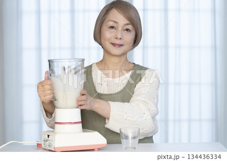 キッチンでヘルシージュースをジューサーで作るシニア女性 キッチンでヘルシージュースをジューサーで作るシニア女性 134436334