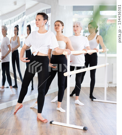 Woman performing battement tendu at barre in ballet studio Woman performing battement tendu at barre in ballet studio 134436381