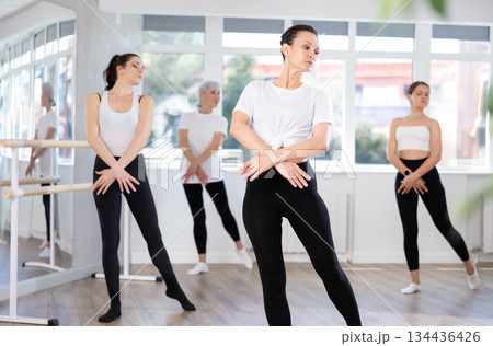 Graceful women of different ages practice various ballet movements in choreographic studio Graceful women of different ages practice various ballet movements in choreographic studio 134436426