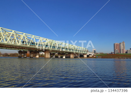 冬の荒川橋梁を渡る京浜東北線E233系電車と川口市街遠景 134437396