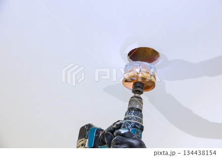 Drilling process in ceiling during home renovation project in bright indoor space 134438154