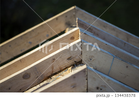 Close-up detail of roof frame of rough wooden lumber beams on background of misty mountain landscape in ecological area. Building, roofing, construction and renovation concept. 134438378