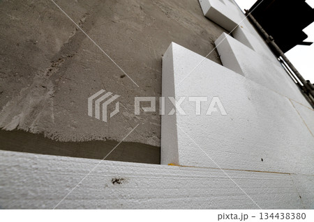 Close-up detail of plastered house wall with rigid styrofoam insulation. Modern technology, construction, renovation, energy saving, alternative for mineral wool, warm comfortable house concept. Close-up detail of plastered house wall with rigid styrofoam insulation. Modern technology, construction, renovation, energy saving, alternative for mineral wool, warm comfortable house concept. 134438380