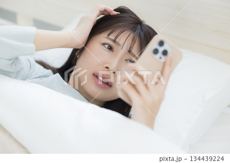 ベッドでスマホを見る女性 134439224