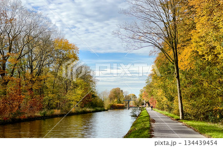 Autumn scenic pathway, Reflective water alongside vibrant fall foliage 134439454