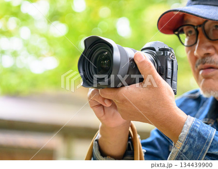 カメラを持つシニア男性の手元と自然光 134439900