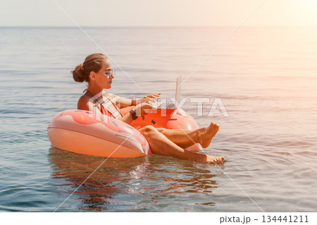 Woman Laptop Beach Working Remotely on Floating Device While Relaxing on Vacation 134441211