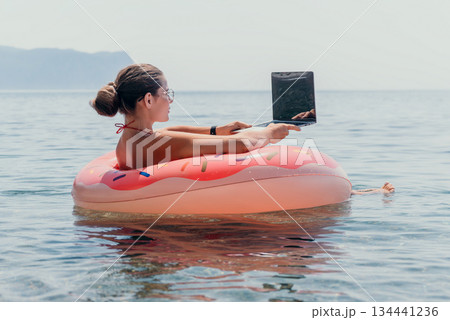 Woman Laptop Beach Floating Donut Inflatable Relaxing Work Remotely Summer Vacation 134441236