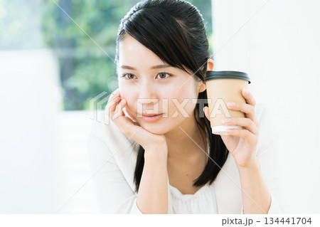 仕事をしながらコーヒーを飲む女性 仕事をしながらコーヒーを飲む女性 134441704