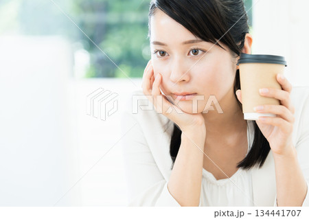 仕事をしながらコーヒーを飲む女性 仕事をしながらコーヒーを飲む女性 134441707