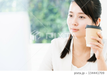 仕事をしながらコーヒーを飲む女性 134441709