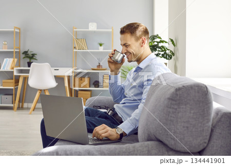 Confident attractive man sitting on sofa at home working or having online video call. 134441901