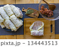Process of making homemade stuffed cabbage rolls with minced meat, rice and spices in a cozy home kitchen. Traditional comfort food preparation, step by step cooking concept. 134443513