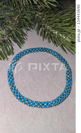 A blue handmade bracelet made of beads and glass beads on a light background. 134443690