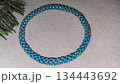 A blue handmade bracelet made of beads and glass beads on a light background. 134443692