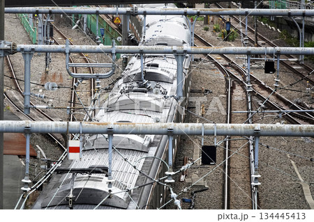 鉄道路線をまたぐ高架歩道橋より電車の上部パンタグラフと架空電車線 134445413