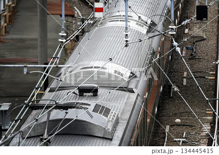 鉄道路線をまたぐ高架歩道橋より電車の上部パンタグラフと架空電車線 134445415