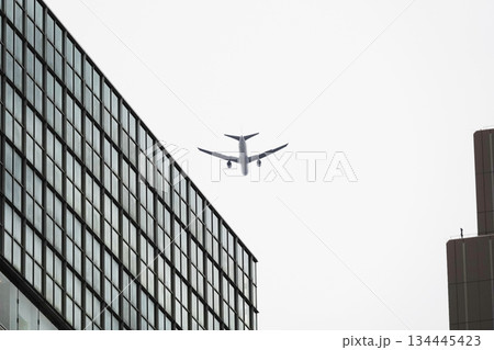 都会の風景 ビルとビルの間を飛行する旅客機 134445423