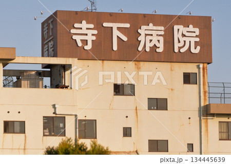 看板下の錆が見立つ老朽化が進む施設で地域医療を死守する現役病院の外観と医療崩壊の危機 134445639