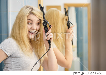 Woman using hair curler 134445779