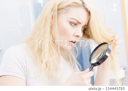 Woman magnifying her split ends hair 134445783