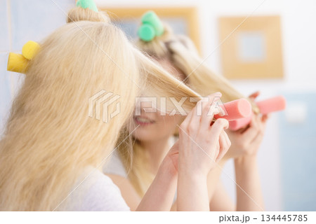 Blonde woman using hair rollers 134445785