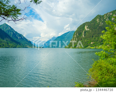 Serene Lake Idro Surrounded by Majestic Mountains and Cloudy sky, Italy, Crone 134446710