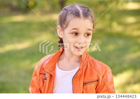 Young caucasian female child with braided hair in orange jacket outdoors Young caucasian female child with braided hair in orange jacket outdoors 134448423