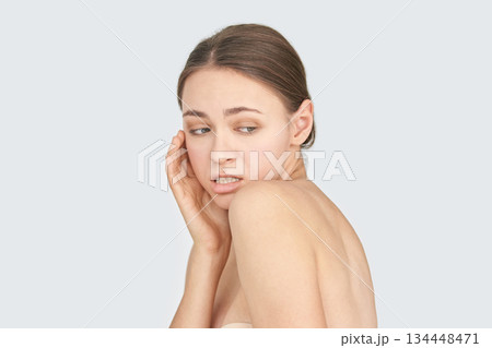 Young caucasian adult female with concerned expression and bare shoulders Young caucasian adult female with concerned expression and bare shoulders 134448471