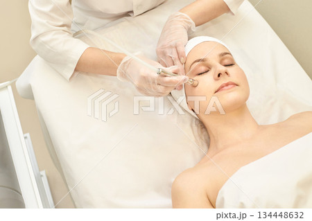 Young caucasian female receiving facial treatment in spa for skin rejuvenation Young caucasian female receiving facial treatment in spa for skin rejuvenation 134448632