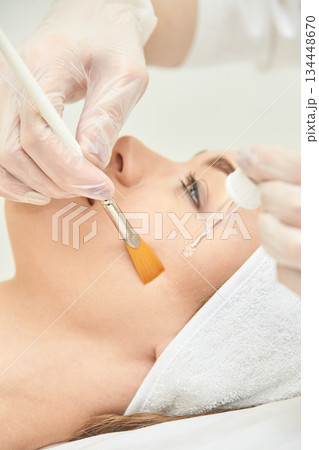 Caucasian female receiving facial treatment with brush and serum in spa setting Caucasian female receiving facial treatment with brush and serum in spa setting 134448670