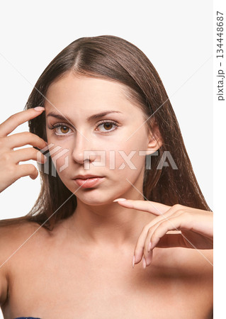 Young caucasian female with long brown hair and natural makeup posing on white 134448687
