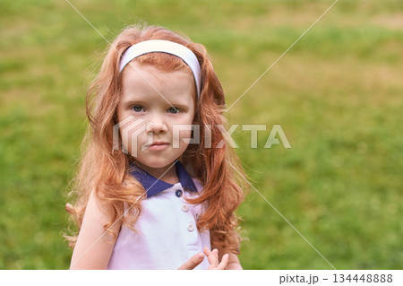 Caucasian young girl with red hair outdoors wearing white headband and pink Caucasian young girl with red hair outdoors wearing white headband and pink 134448888