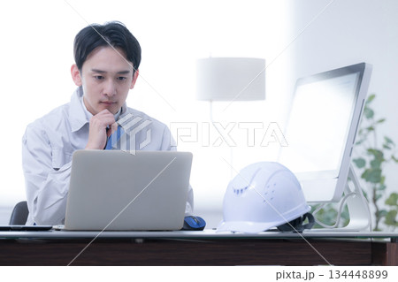現場事務所で考える作業着の作業員 発注や下請けで納期に困るや経営などの戦略を考える 現場事務所で考える作業着の作業員 発注や下請けで納期に困るや経営などの戦略を考える 134448899