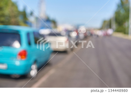 Blurry image of cars on a street in daylight with green car in focus 134448980