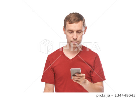 Caucasian young adult male in red shirt using smartphone on white background Caucasian young adult male in red shirt using smartphone on white background 134449043