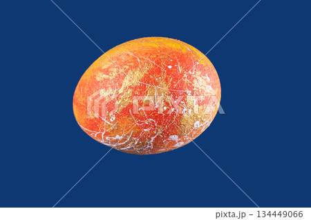 Colorful abstract painted egg with gold and red design on plain blue background Colorful abstract painted egg with gold and red design on plain blue background 134449066