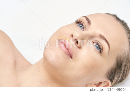 Young caucasian female receiving facial waxing treatment for smooth skin Young caucasian female receiving facial waxing treatment for smooth skin 134449094