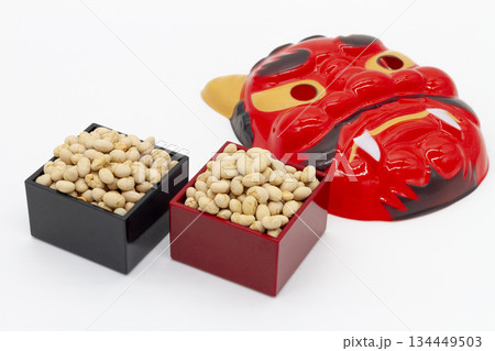 白背景に並んだ黒と朱の枡入り煎り大豆と赤鬼の面 節分・豆まきイメージ 134449503