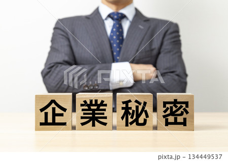 「企業秘密」と書かれたブロックと腕組みをするビジネスマン 134449537