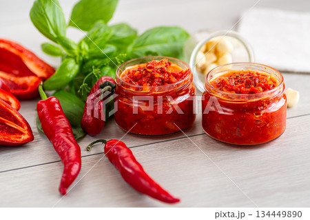 Delicious chili paste with garlic and basil on wooden surface 134449890