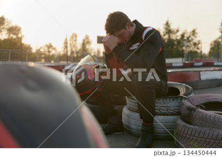 Sad go-kart racer sits in deep thought, reflecting on his performance at the track Sad go-kart racer sits in deep thought, reflecting on his performance at the track 134450444