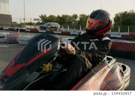A passionate racer skillfully drives a gokart with great determination on an outdoor track 134450457