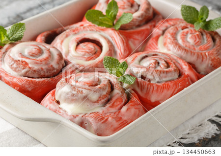 Festive pink cinnabons, cinnamon rolls with white icing, close-up in a baking pan. Horizontal 134450663