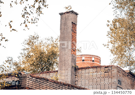 An old abandoned brick building. An old brick chimney. An abandoned, dilapidated building. 134450770