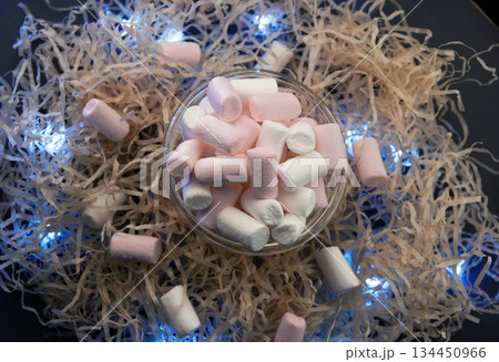 White and pink marshmallows in a transparent cup with a garland. 134450966