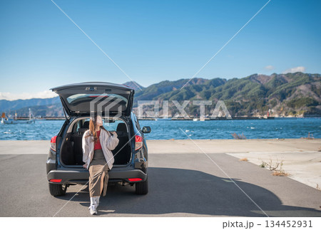 青空のもと海の近くに駐車し休憩する若い女性 134452931